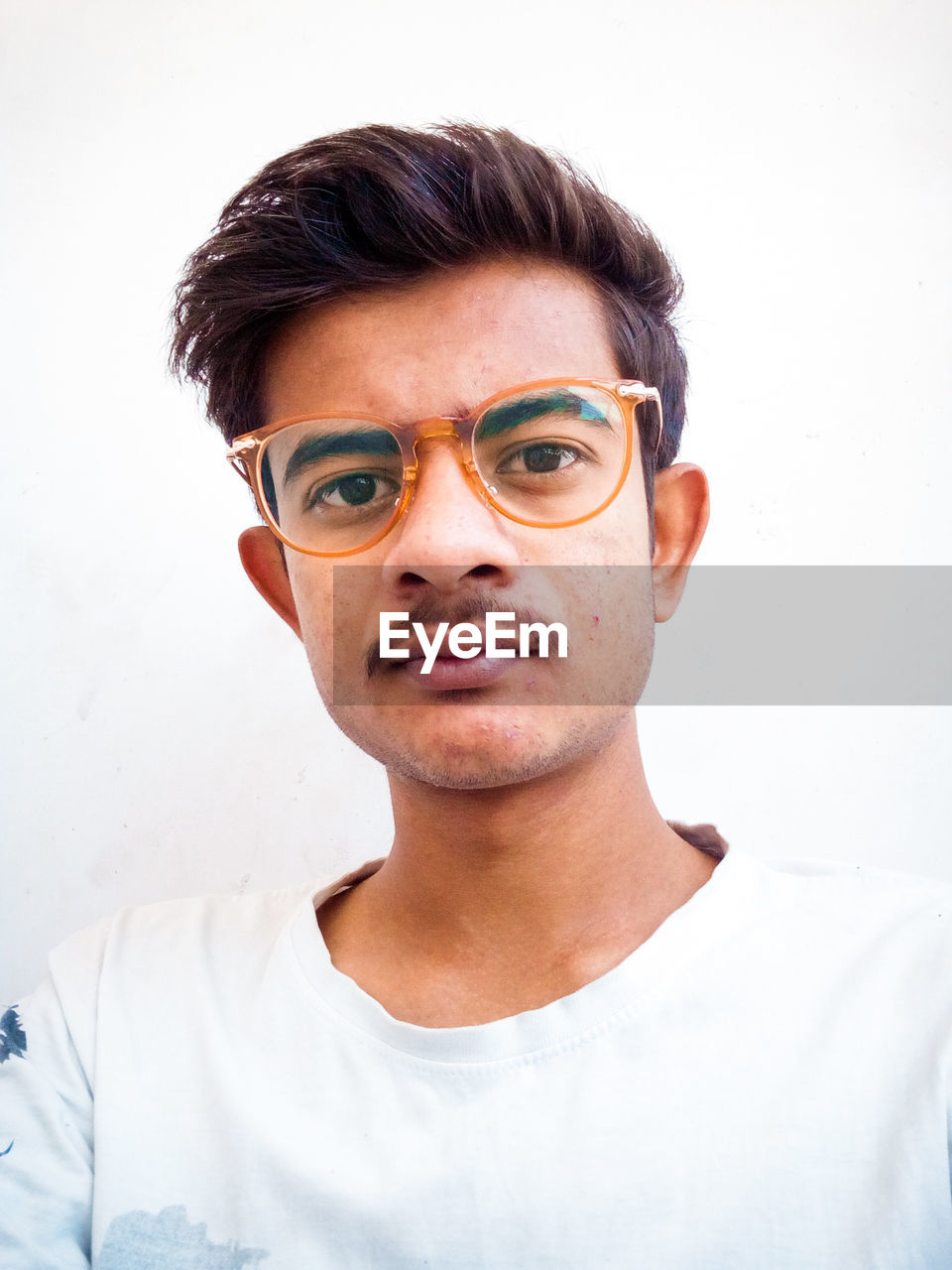 Portrait of young man in eyeglasses against white background