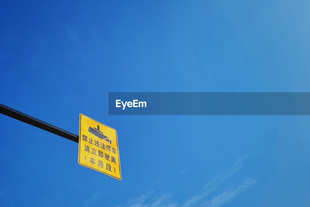 Low angle view of road sign against blue sky