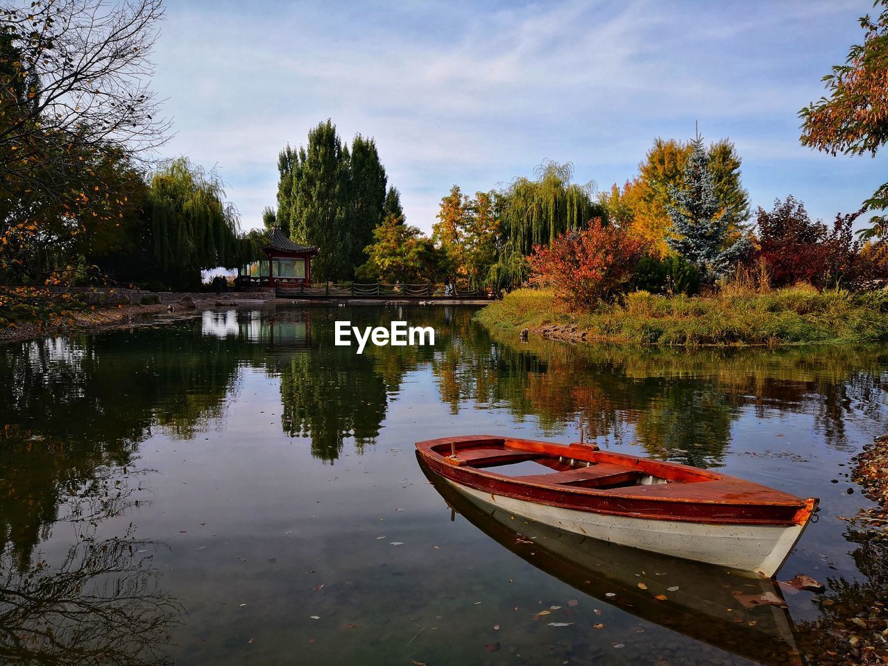 Boat moored in lake against sky during autumn