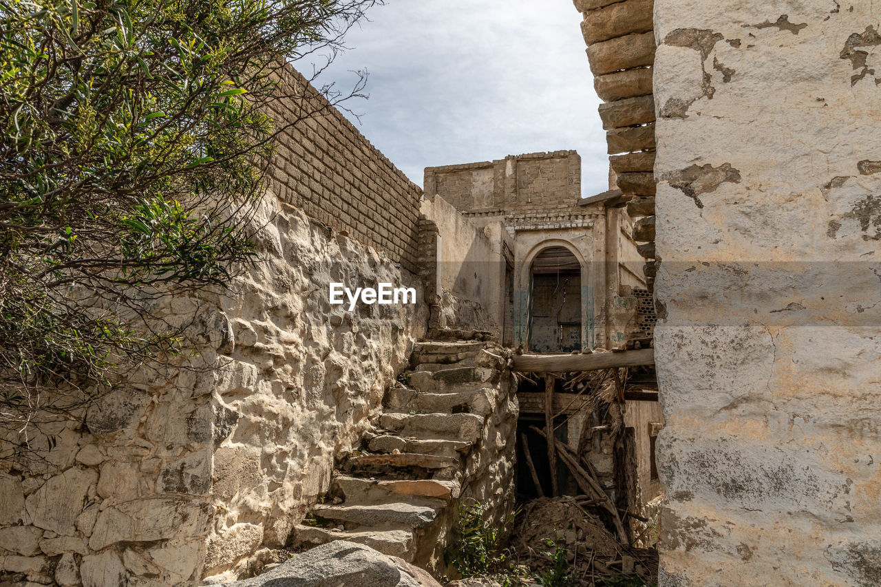 LOW ANGLE VIEW OF OLD BUILDING BY WALL