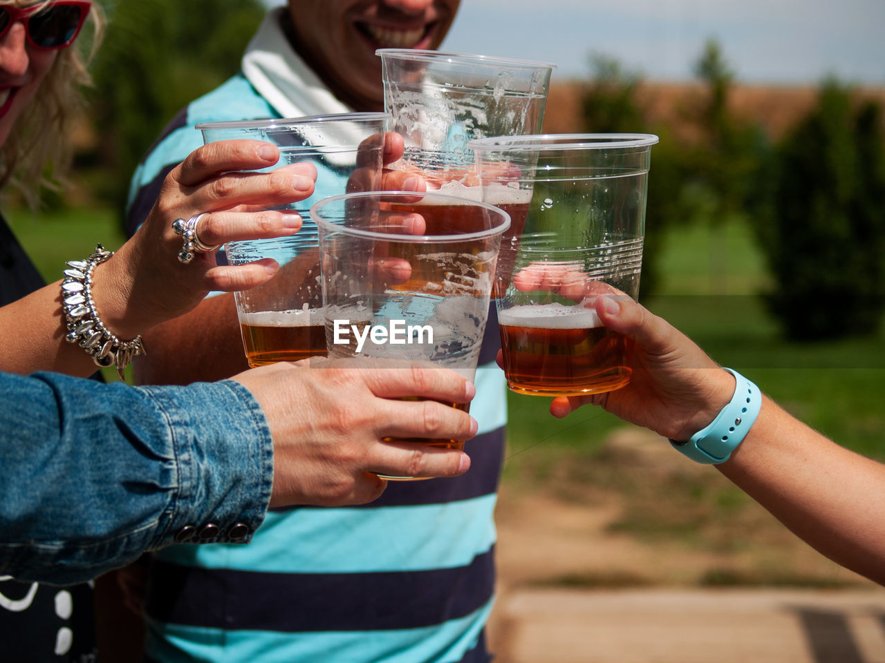 Cropped hands of people drinking beer in glass