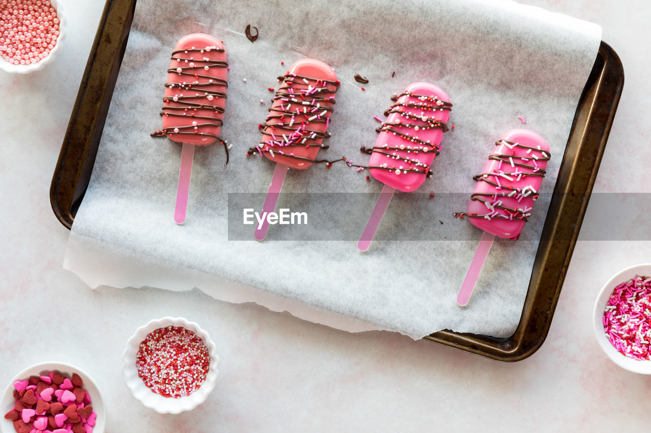 Homemade cakesicles drizzled with candy melts and decorated with sprinkles.