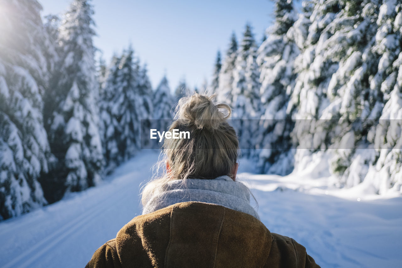 Rear view of woman by snow covered trees during winter