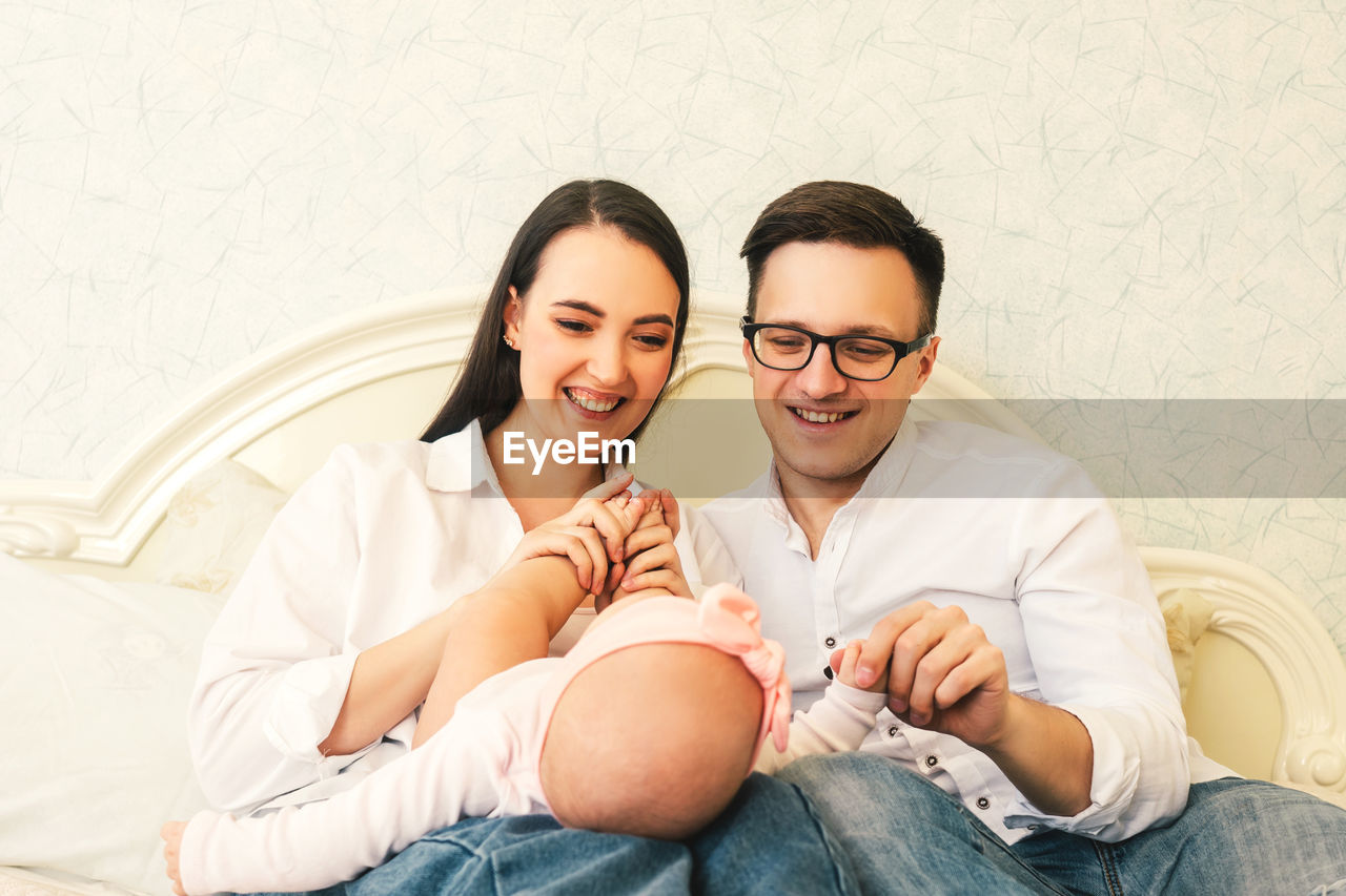 Smiling parents playing with baby girl in bedroom