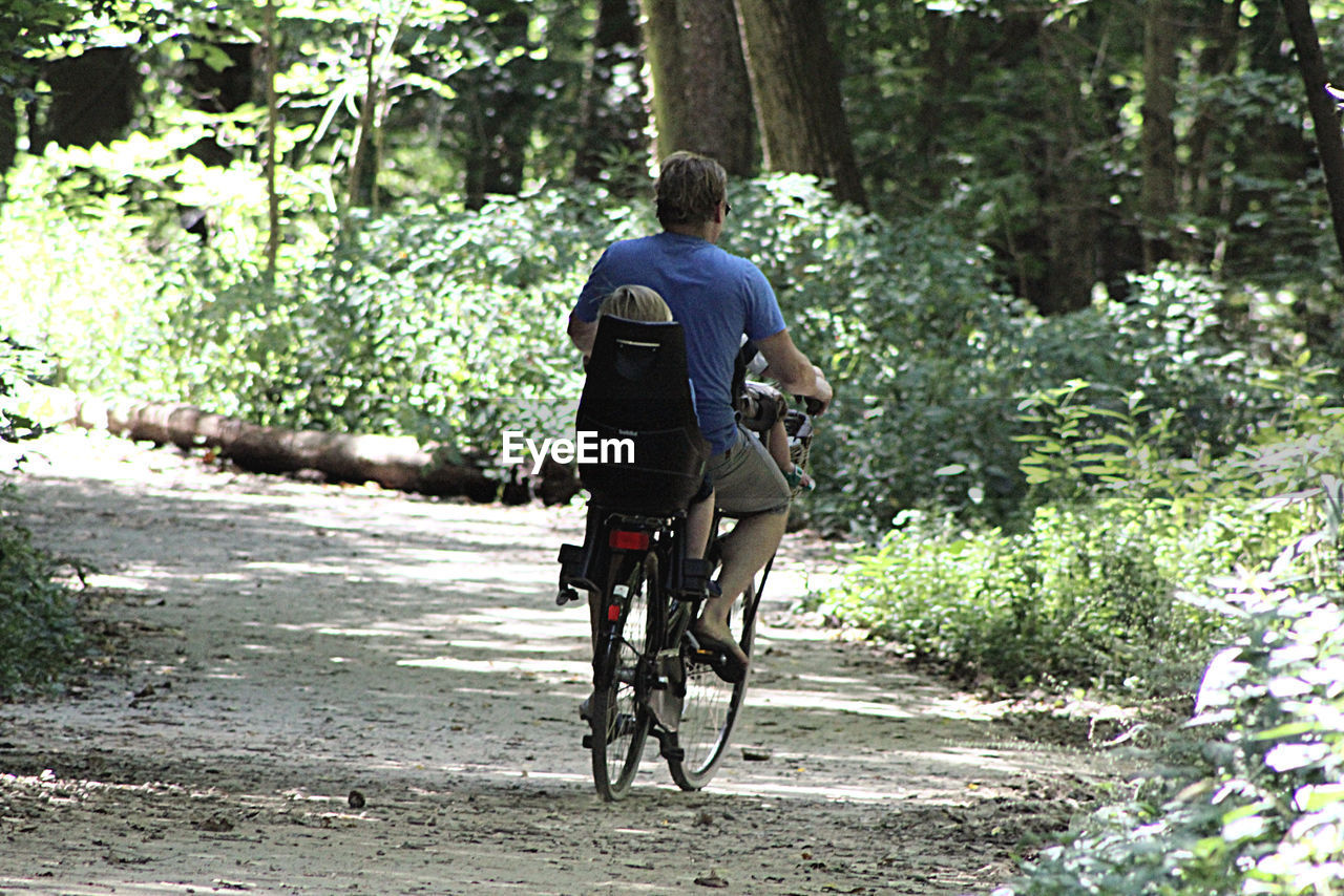 REAR VIEW OF PEOPLE RIDING BICYCLE