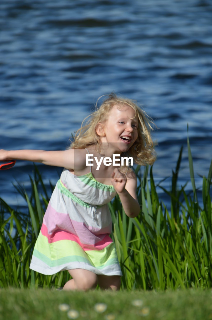 Cute cheerful girl running on grass during summer