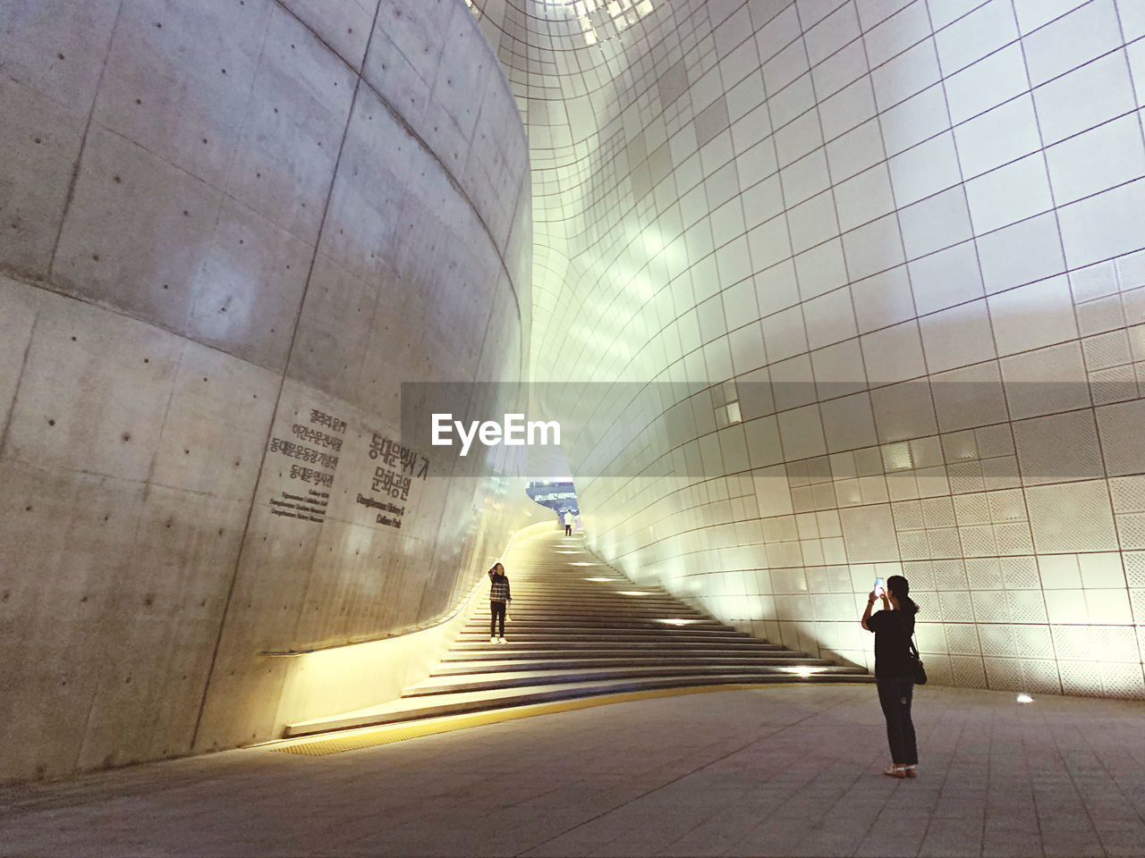 REAR VIEW OF PEOPLE WALKING IN SUBWAY TUNNEL