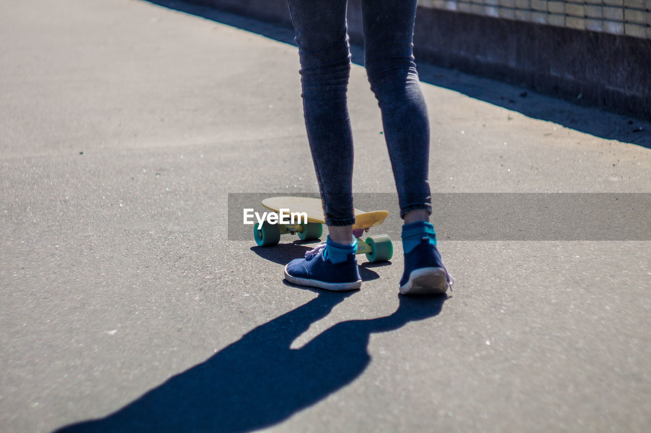 Low section of woman skateboarding on road