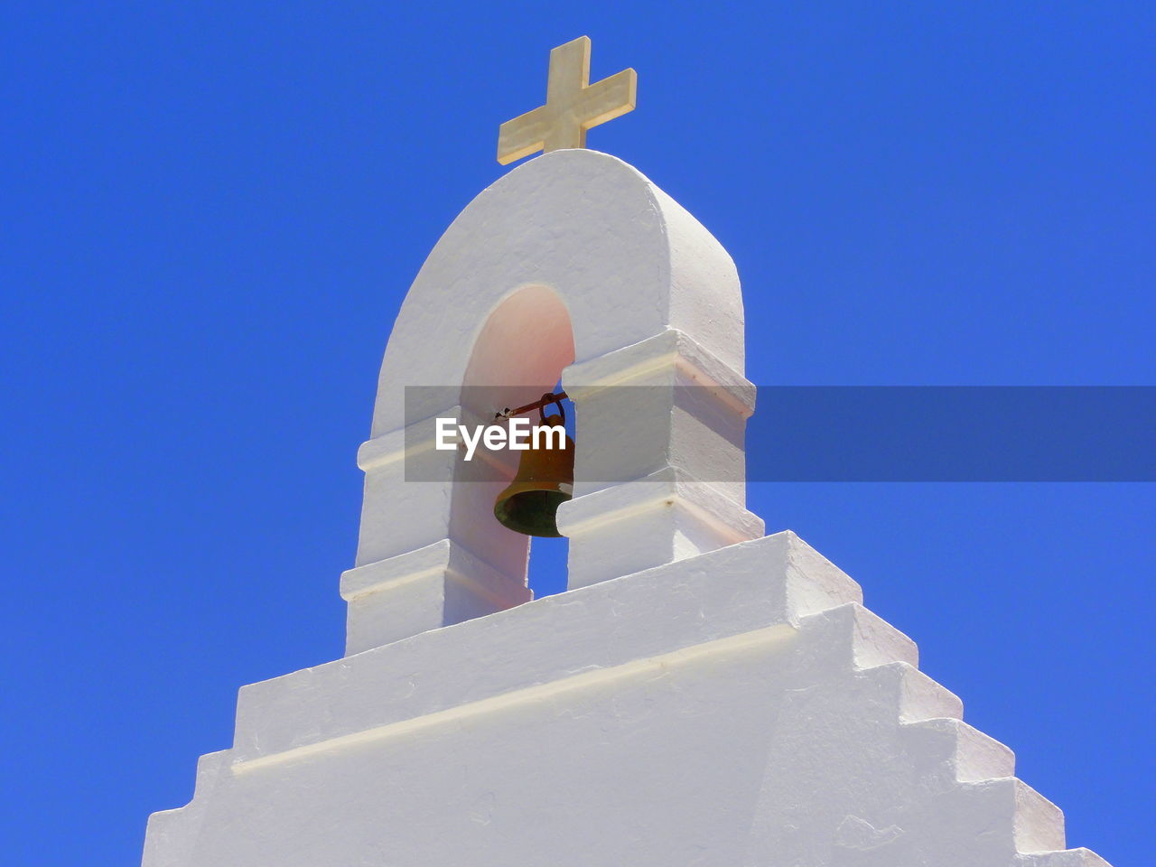 Low angle view of bell tower against clear blue sky on sunny day