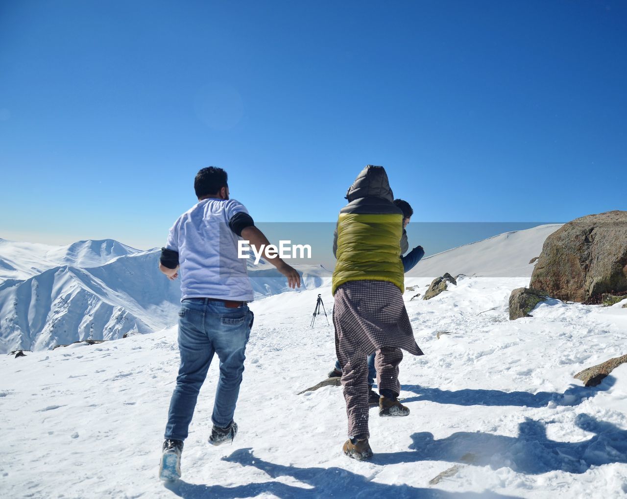 REAR VIEW OF MAN STANDING ON SNOW COVERED MOUNTAIN