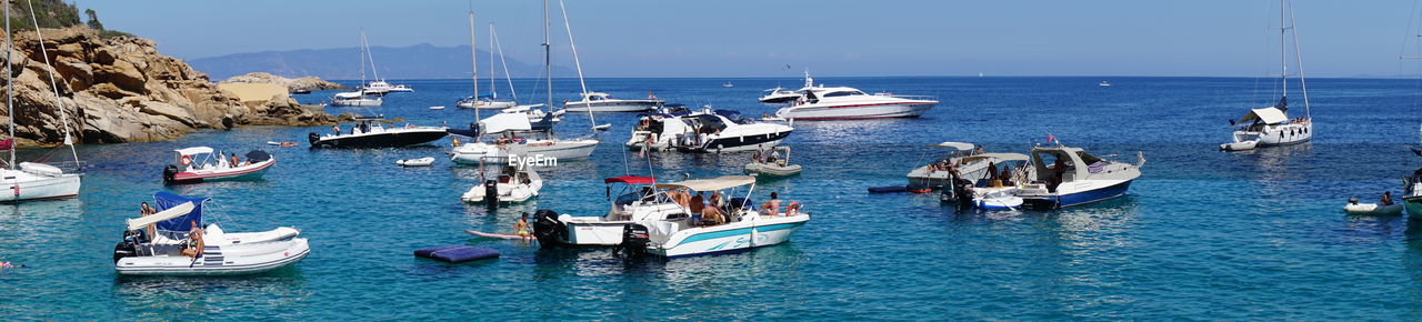 Boats sailing in sea against clear sky