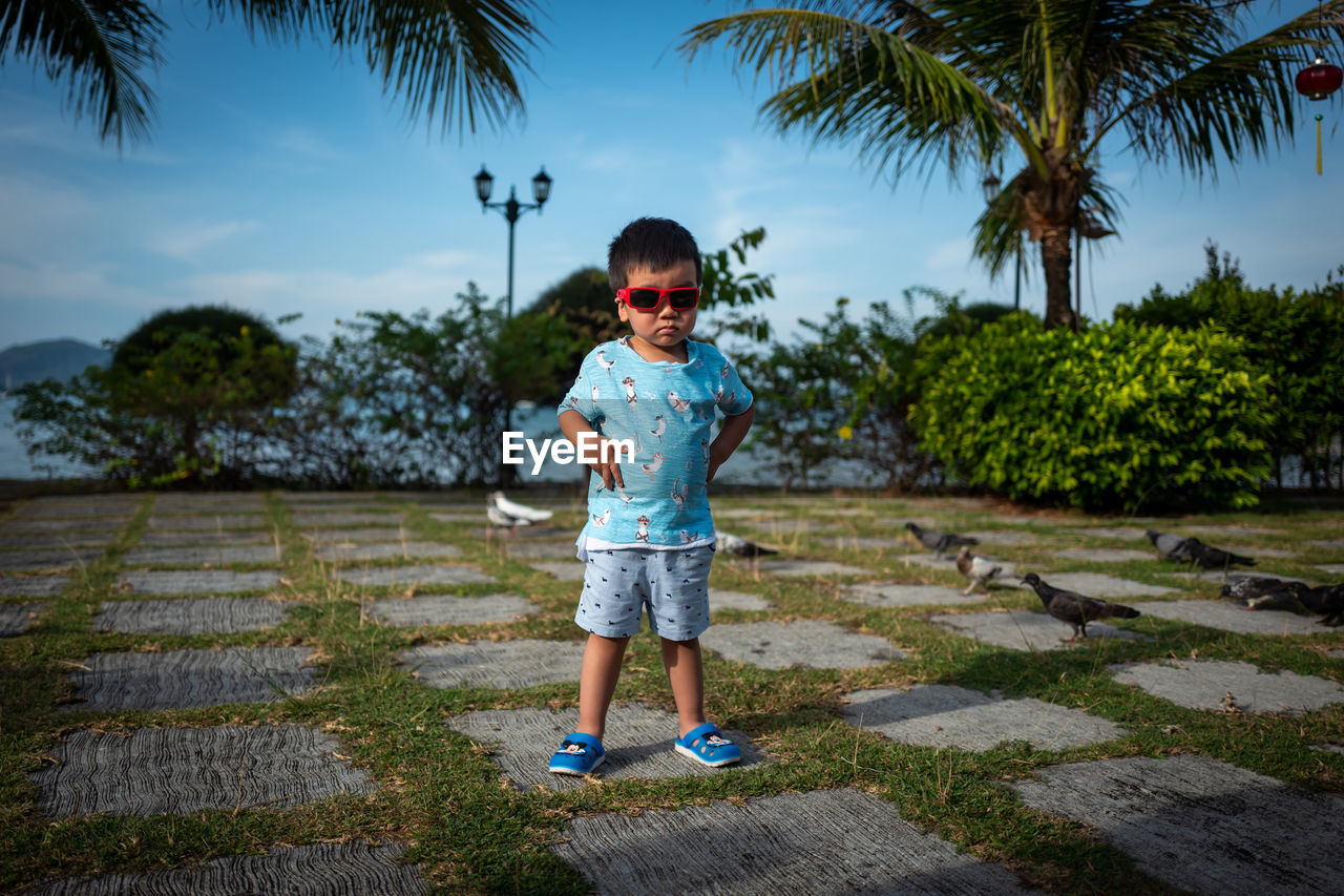 BOY STANDING AGAINST TREES AND PLANTS