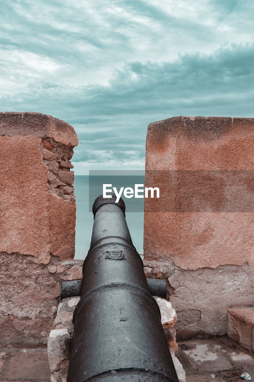 A cannon on the wall pointing at sea