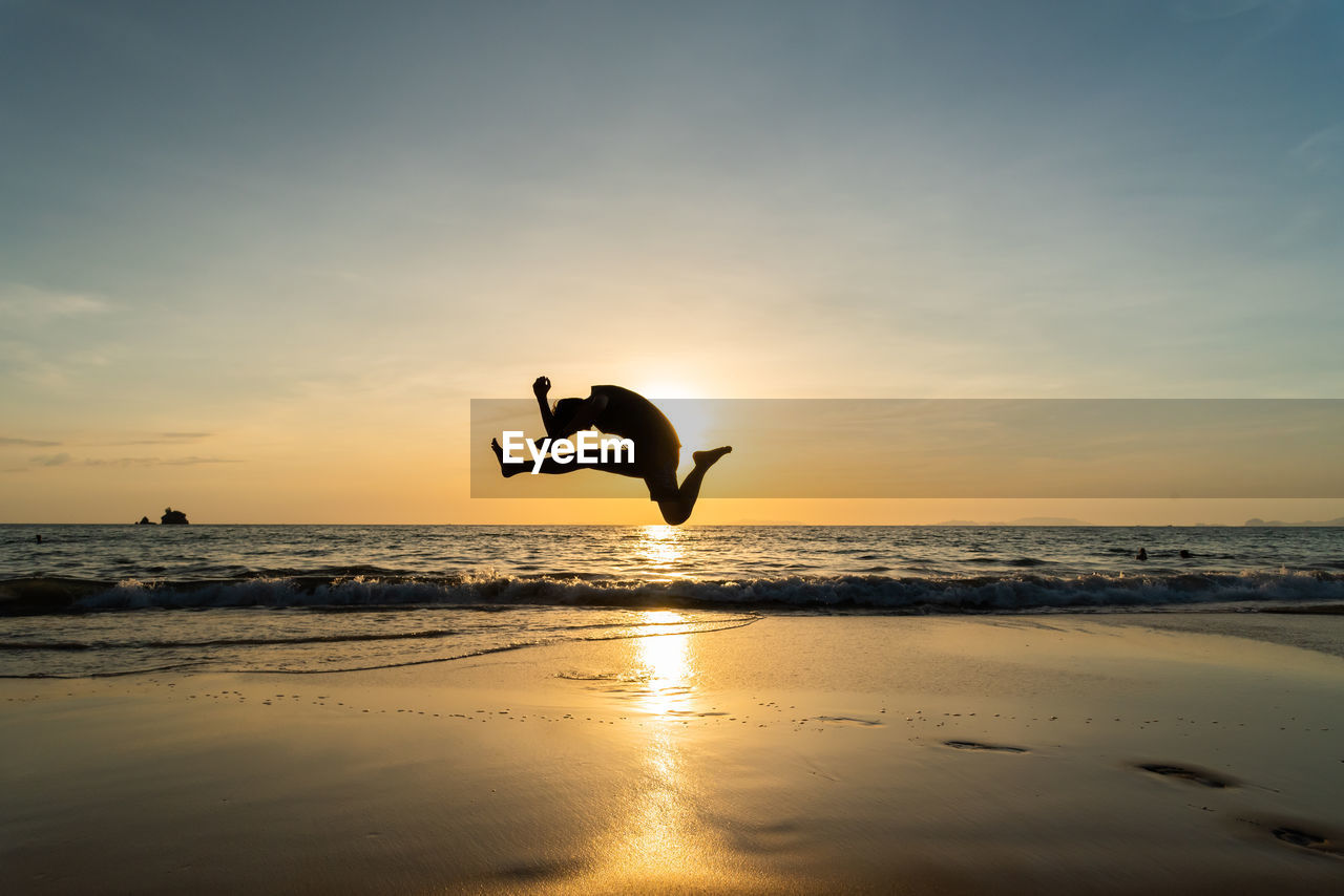 Silhouette man jump when sunset at phayam island, ranong, thailand.