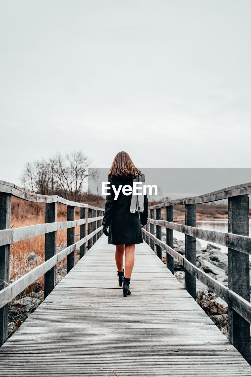 Rear view of woman walking on footbridge