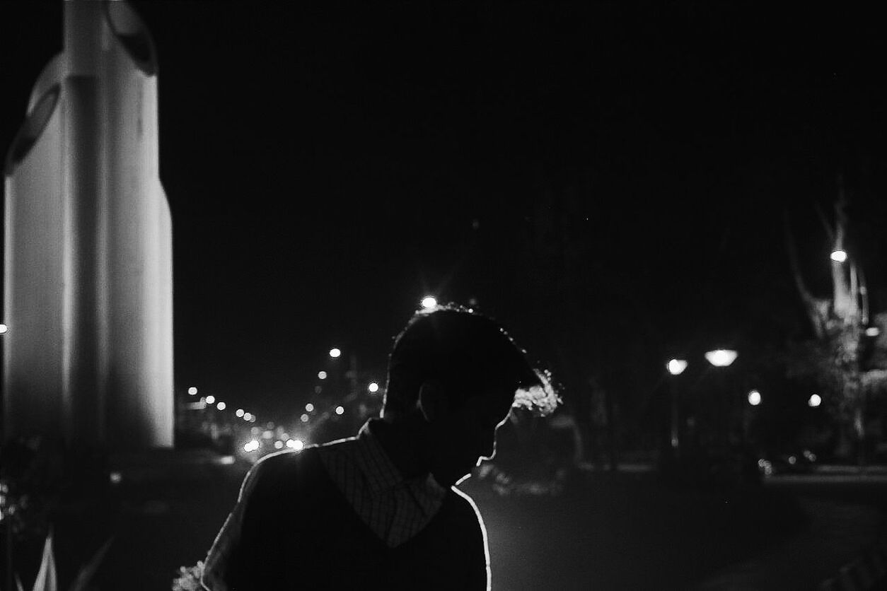 REAR VIEW OF MAN WITH ARMS OUTSTRETCHED AT MUSIC CONCERT