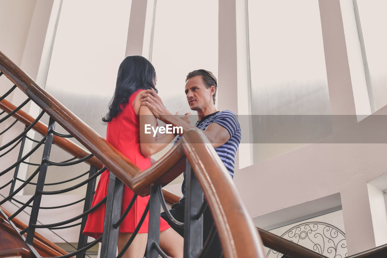 Low angle view of father scolding daughter while standing on staircase at home