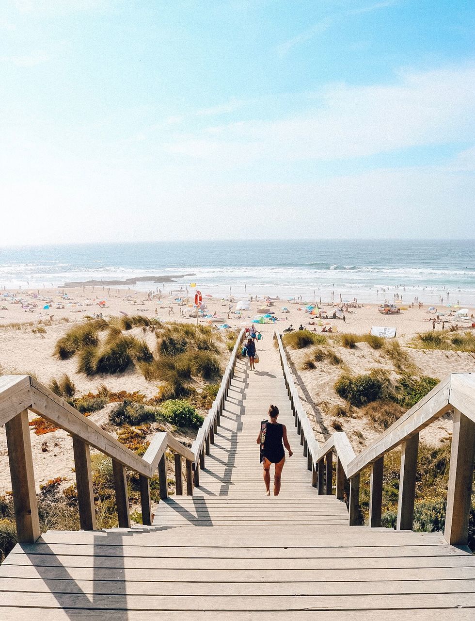 Rear view of woman walking on walkway towards beach 