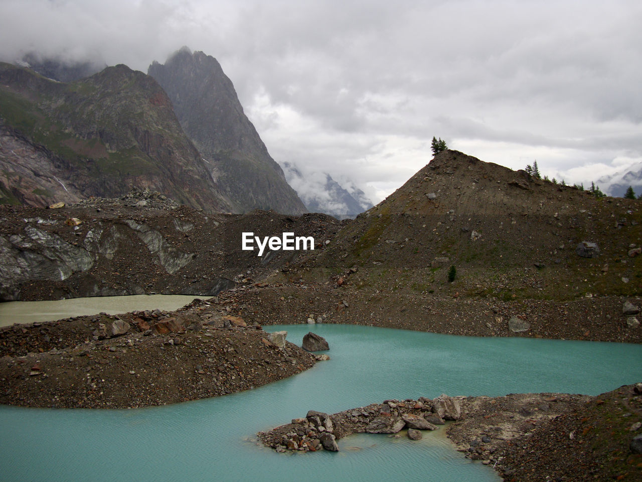 Scenic view of lake at mountains against cloudy sky