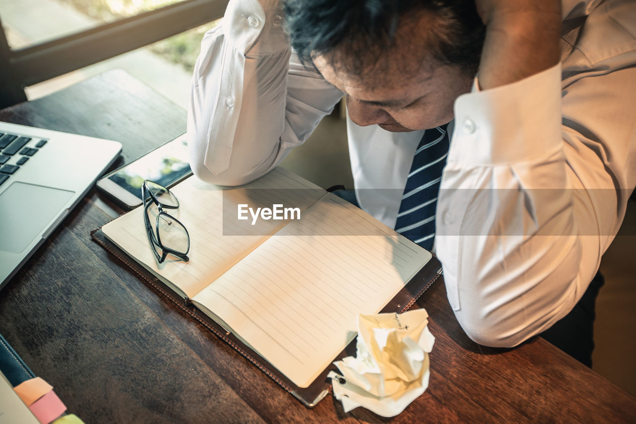 HIGH ANGLE VIEW OF MAN WORKING ON TABLE AT CAFE