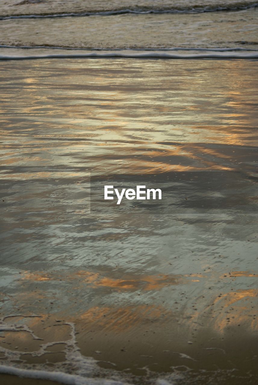 Reflection of sky on wet sand at beach