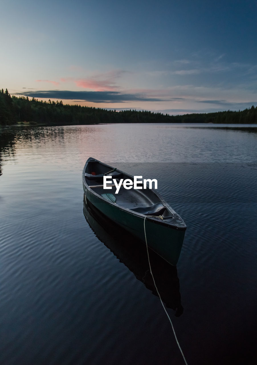 BOAT MOORED ON LAKE AGAINST SKY