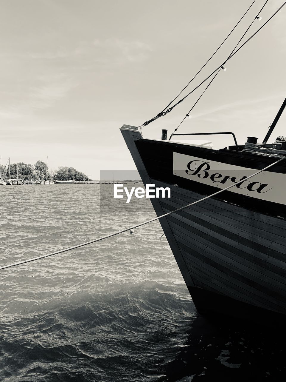 BOAT MOORED ON SHORE AGAINST SKY