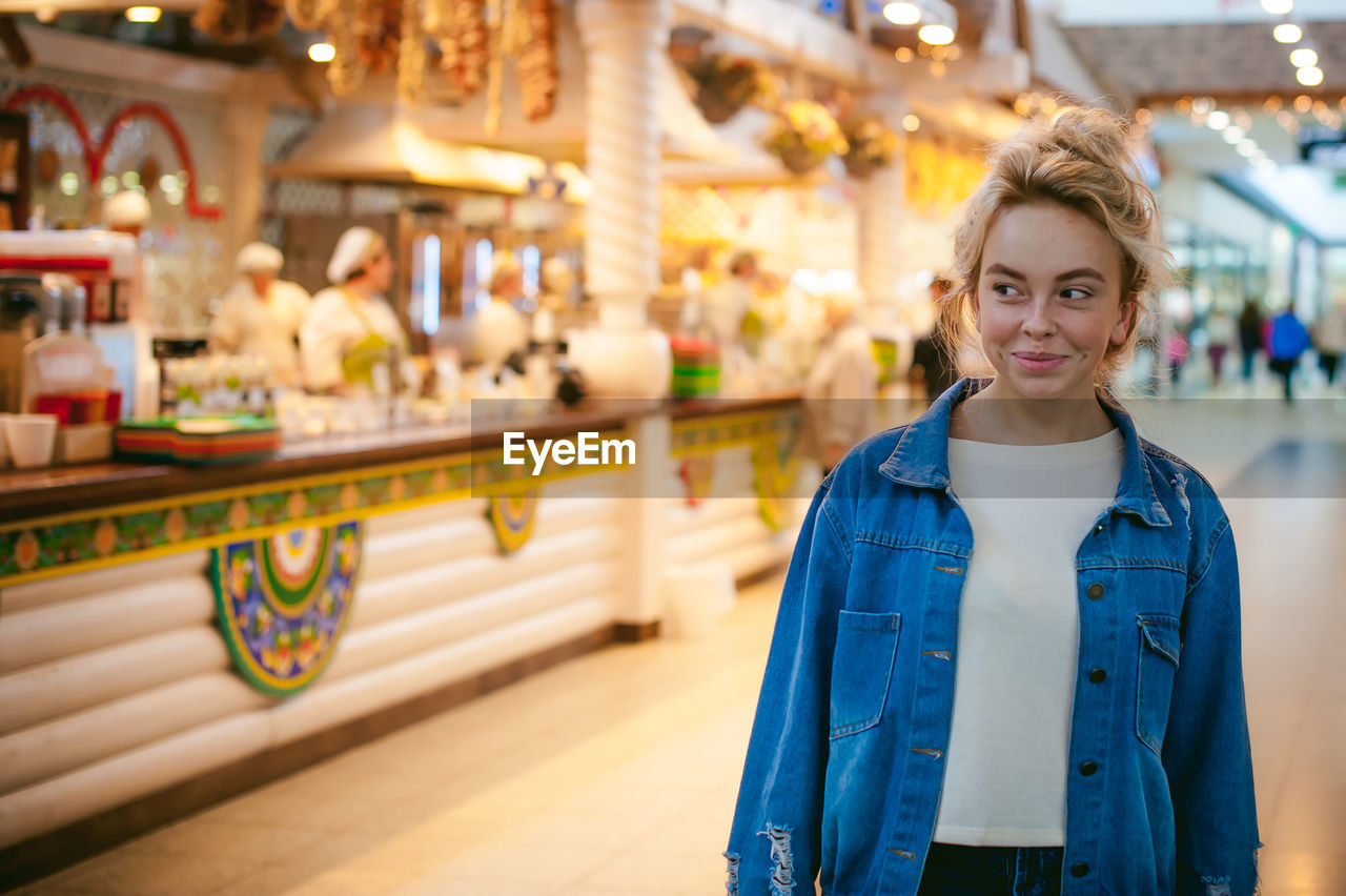 Smiling young woman standing in illuminated market