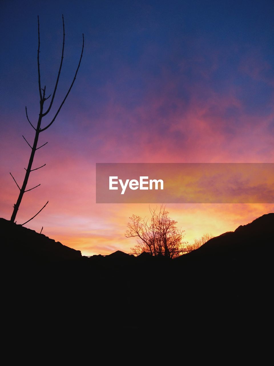 Low angle view of silhouette mountain against cloudy sky at sunset