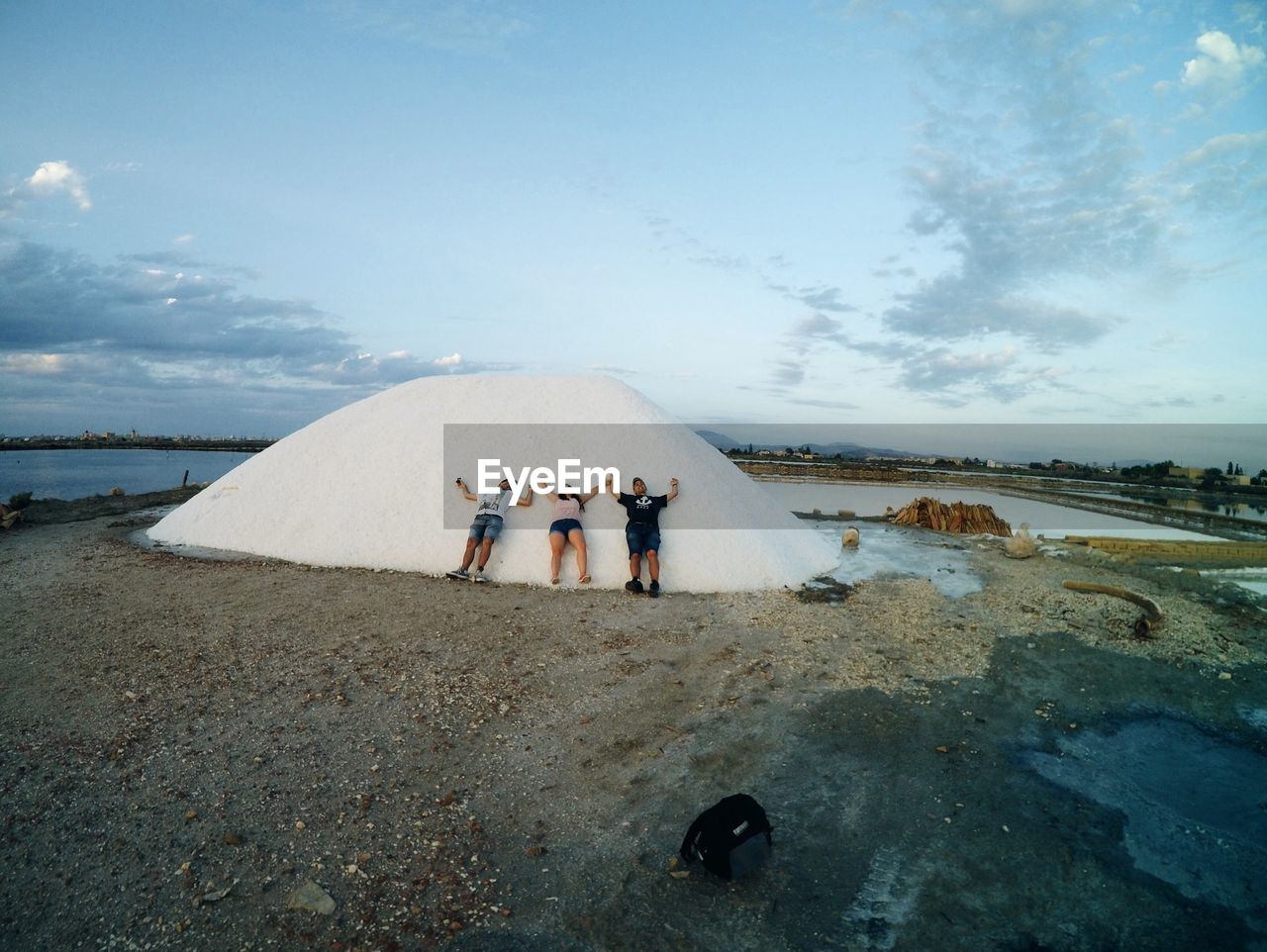 REAR VIEW OF PEOPLE STANDING ON SHORE AGAINST SKY