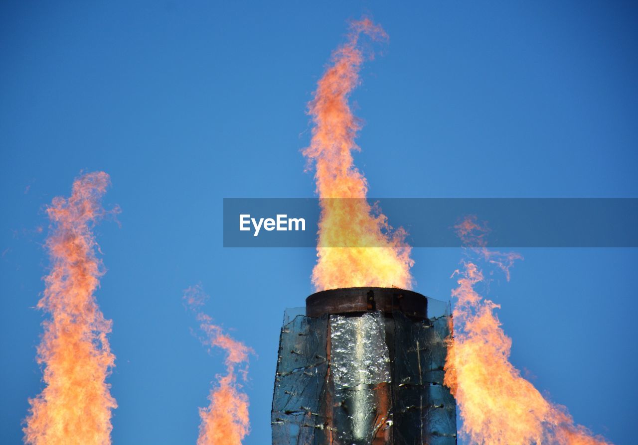 LOW ANGLE VIEW OF SMOKE STACKS AGAINST CLEAR BLUE SKY