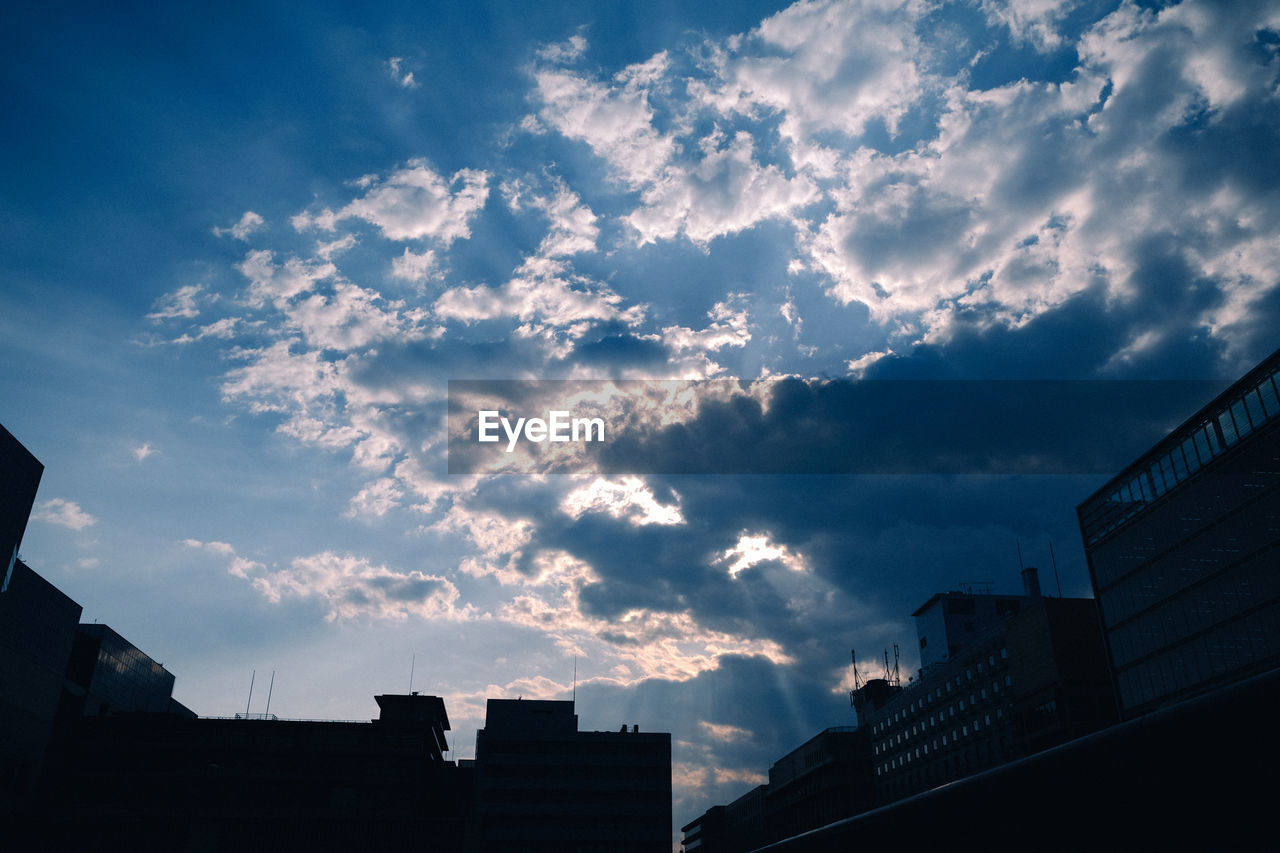 Low angle view of buildings against cloudy sky during sunset