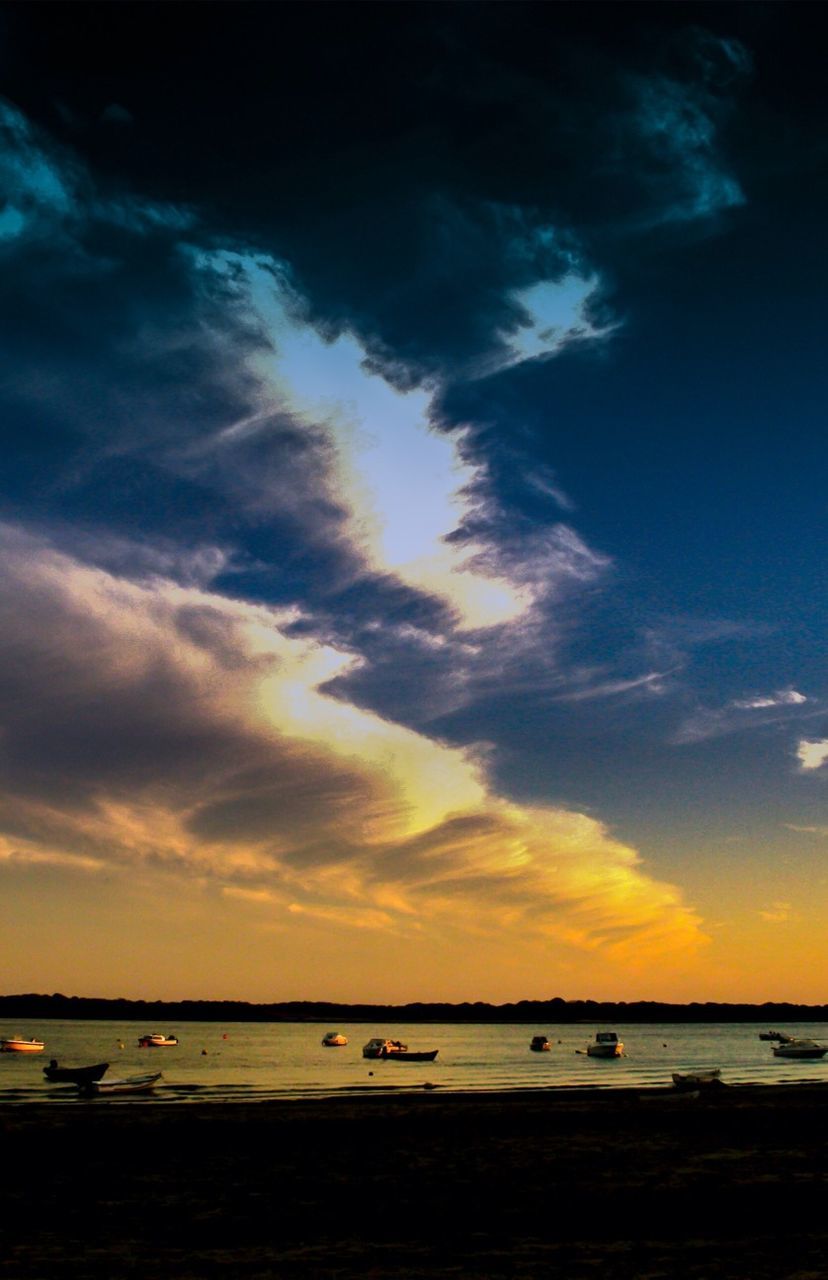 Boats in lake against cloudy sky