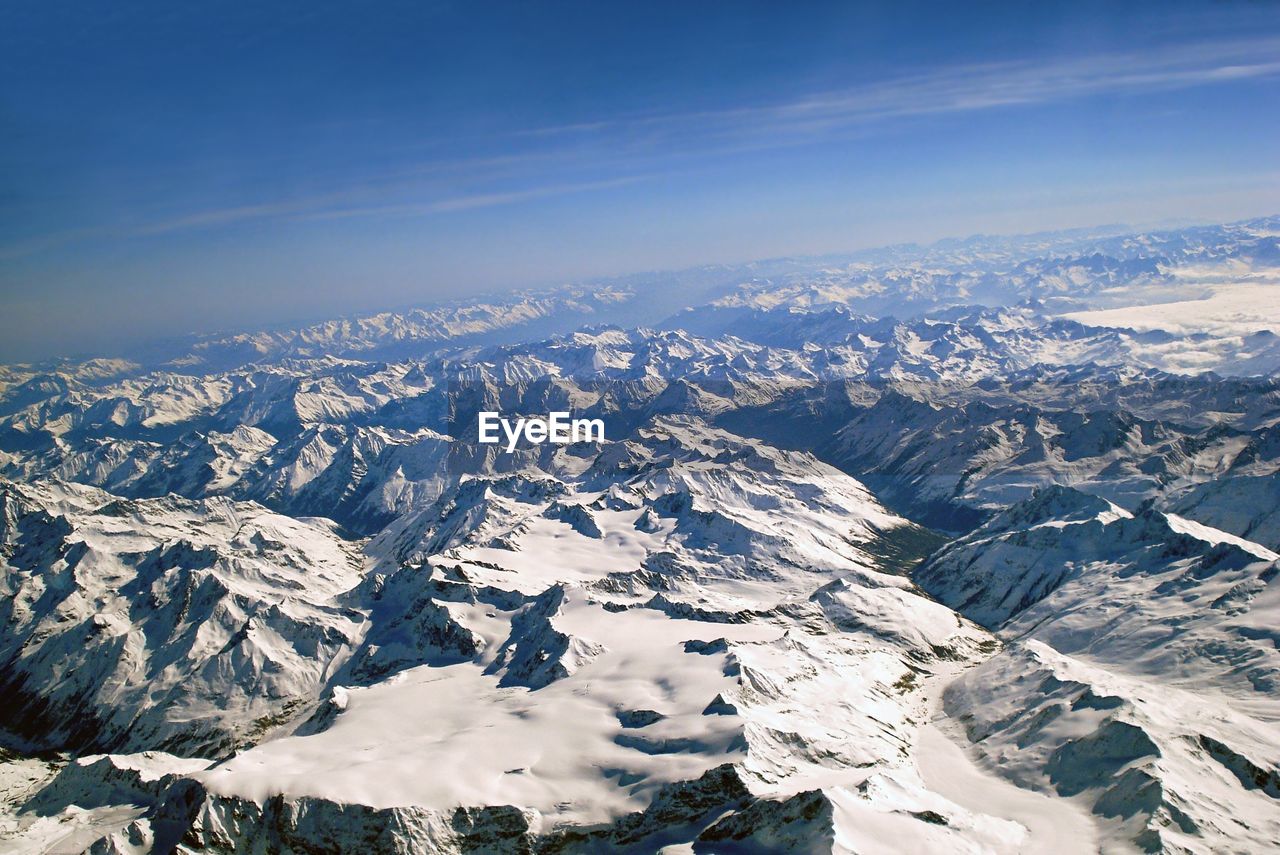 AERIAL VIEW OF SNOW COVERED MOUNTAINS AGAINST SKY