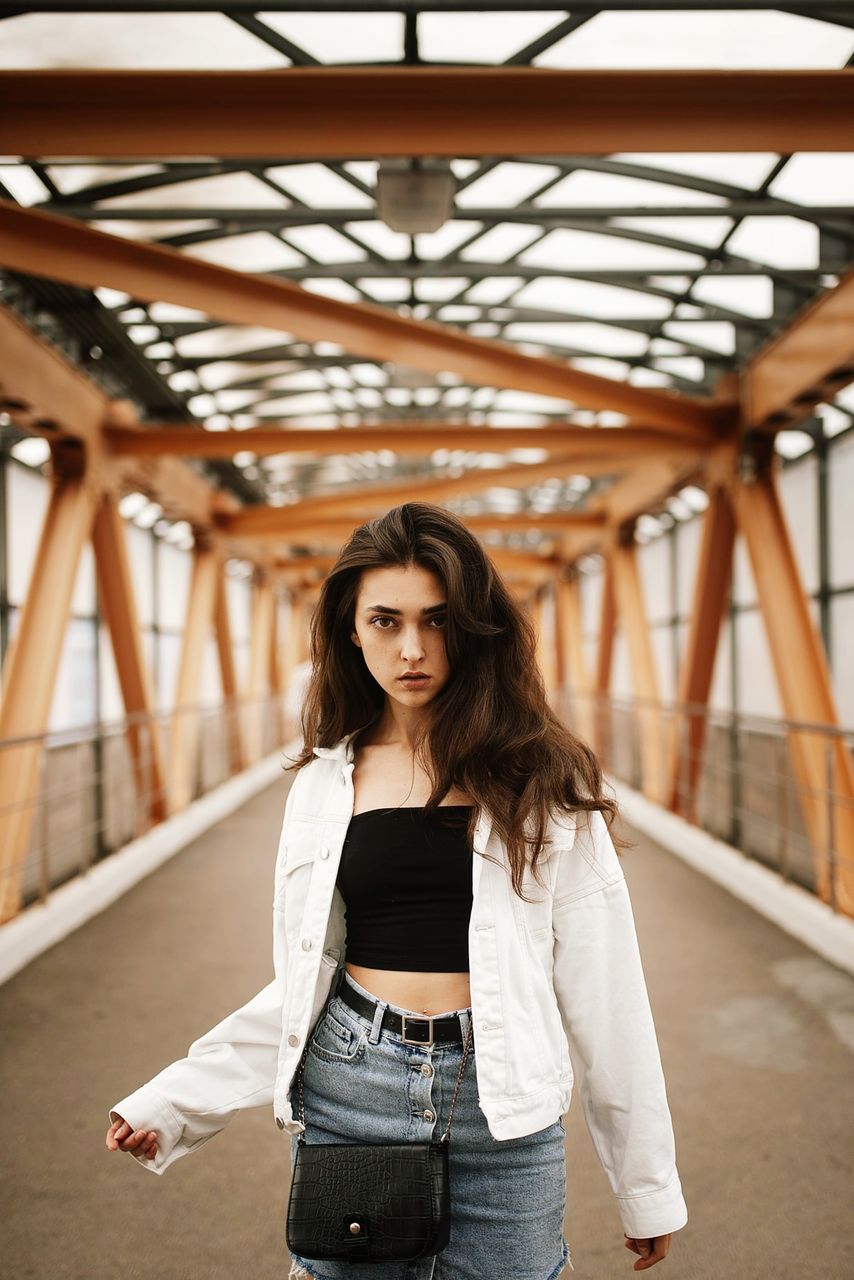 PORTRAIT OF BEAUTIFUL WOMAN STANDING AGAINST BRIDGE