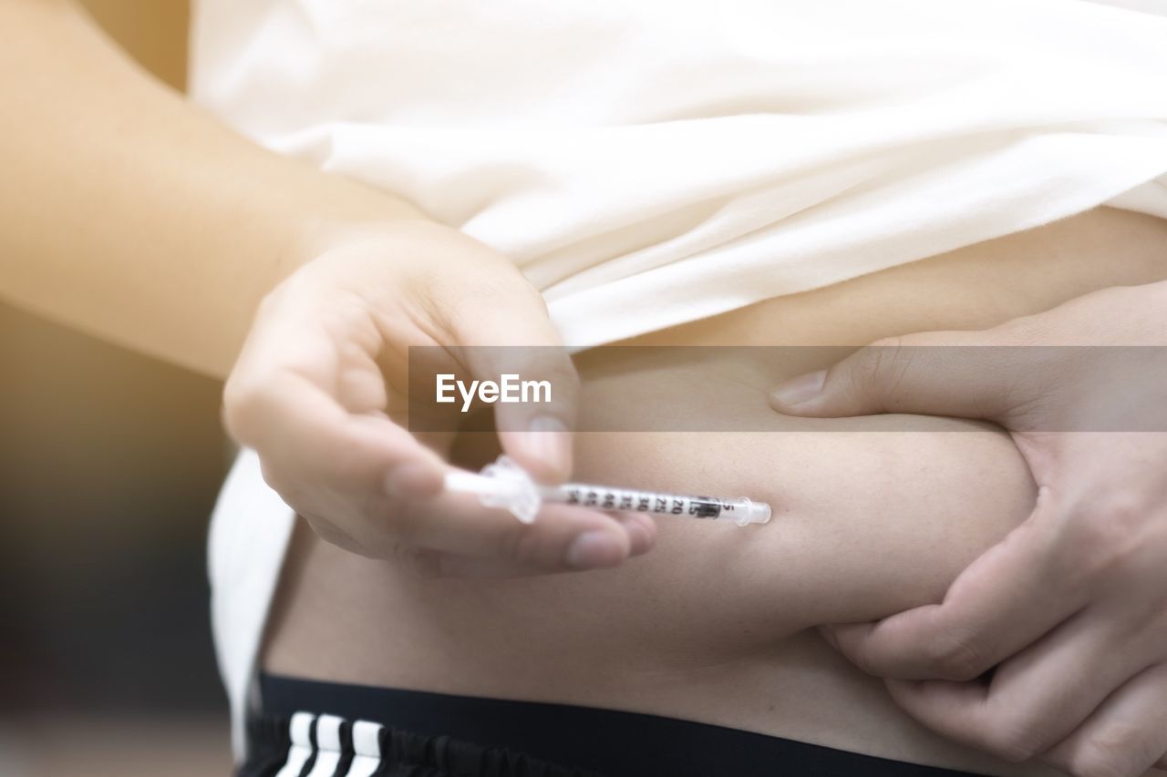Midsection of woman injecting syringe