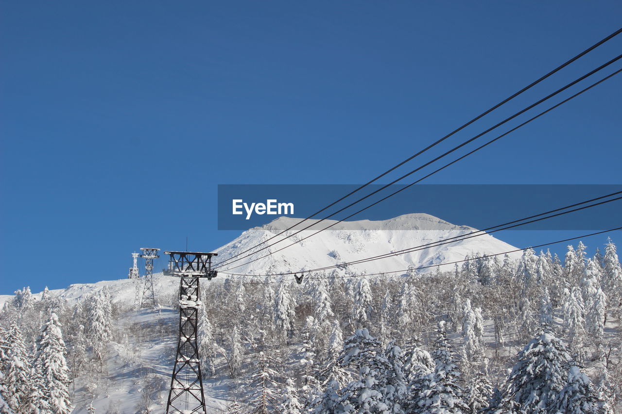 Low angle view of snow covered mountain against clear blue sky