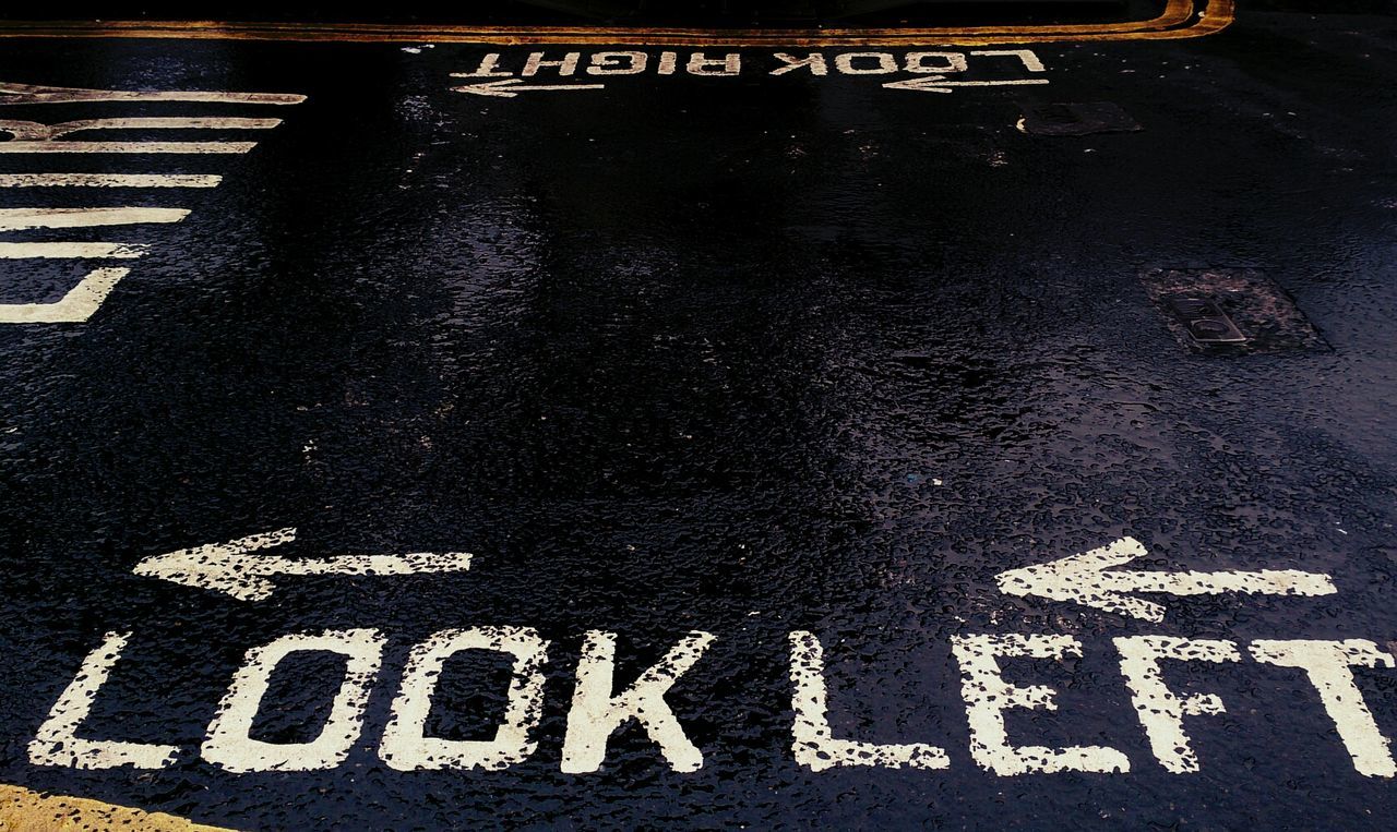 Close-up of look left and arrow signs on road