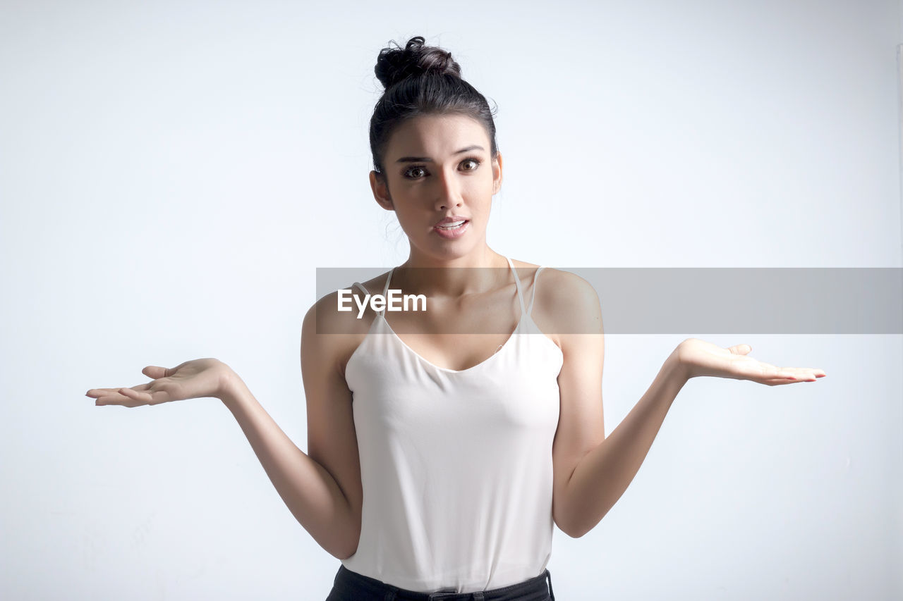 Tensed young woman standing against white background