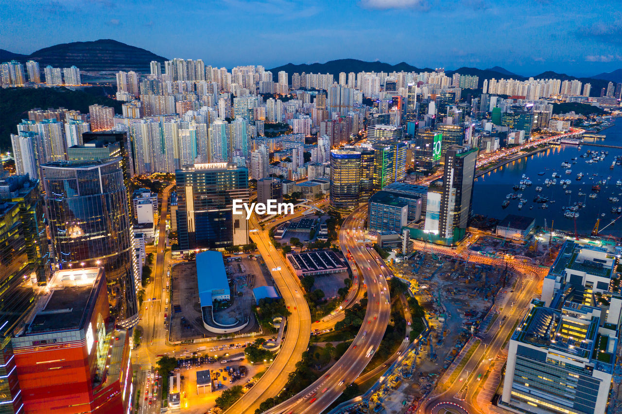 Aerial view of illuminated street amidst buildings in city at dusk