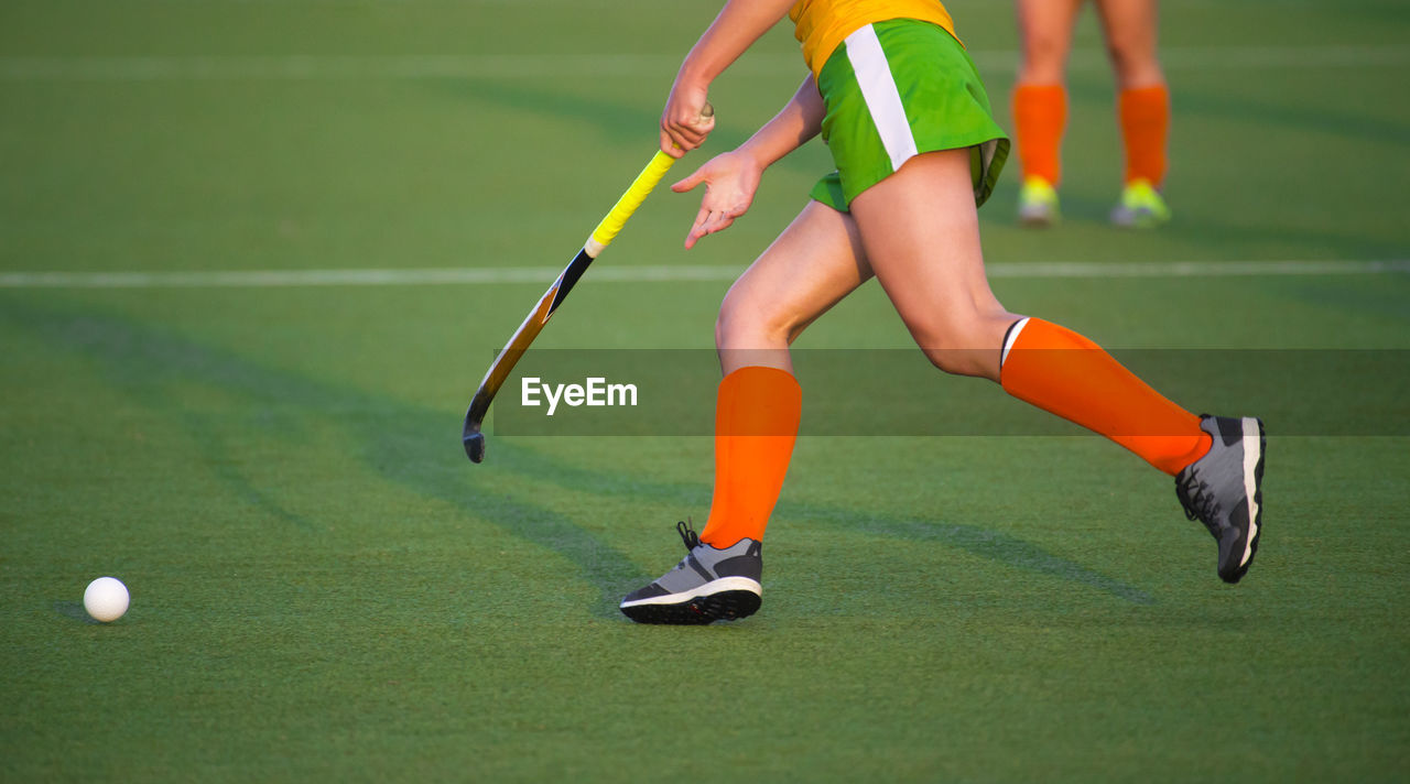 Low section of woman playing hockey in court