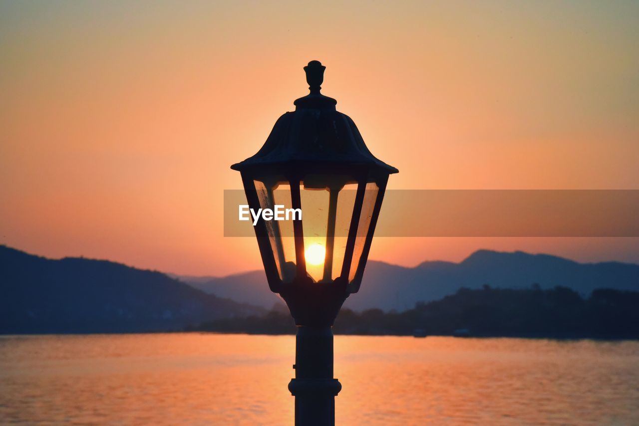 CLOSE-UP OF SILHOUETTE WATER AGAINST ORANGE SKY