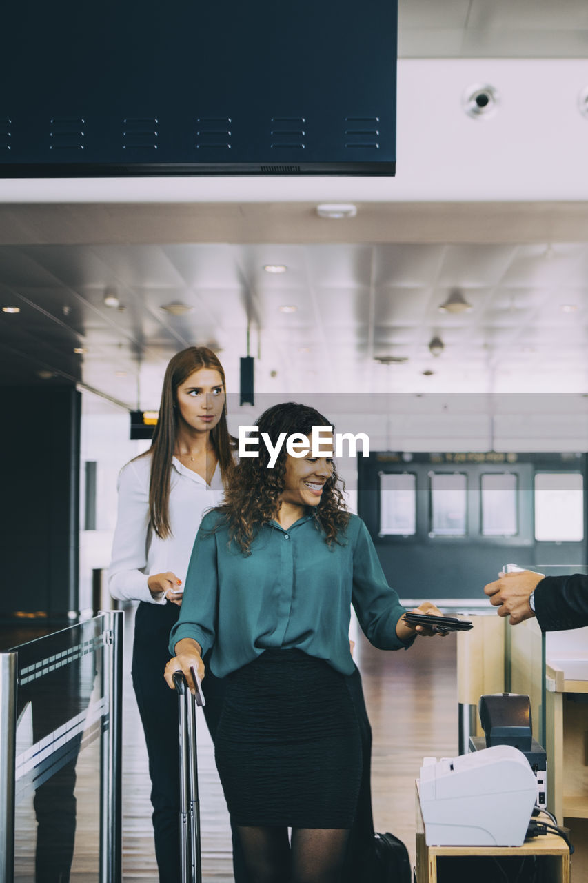 Multi-ethnic female colleagues going through check-in counter at airport