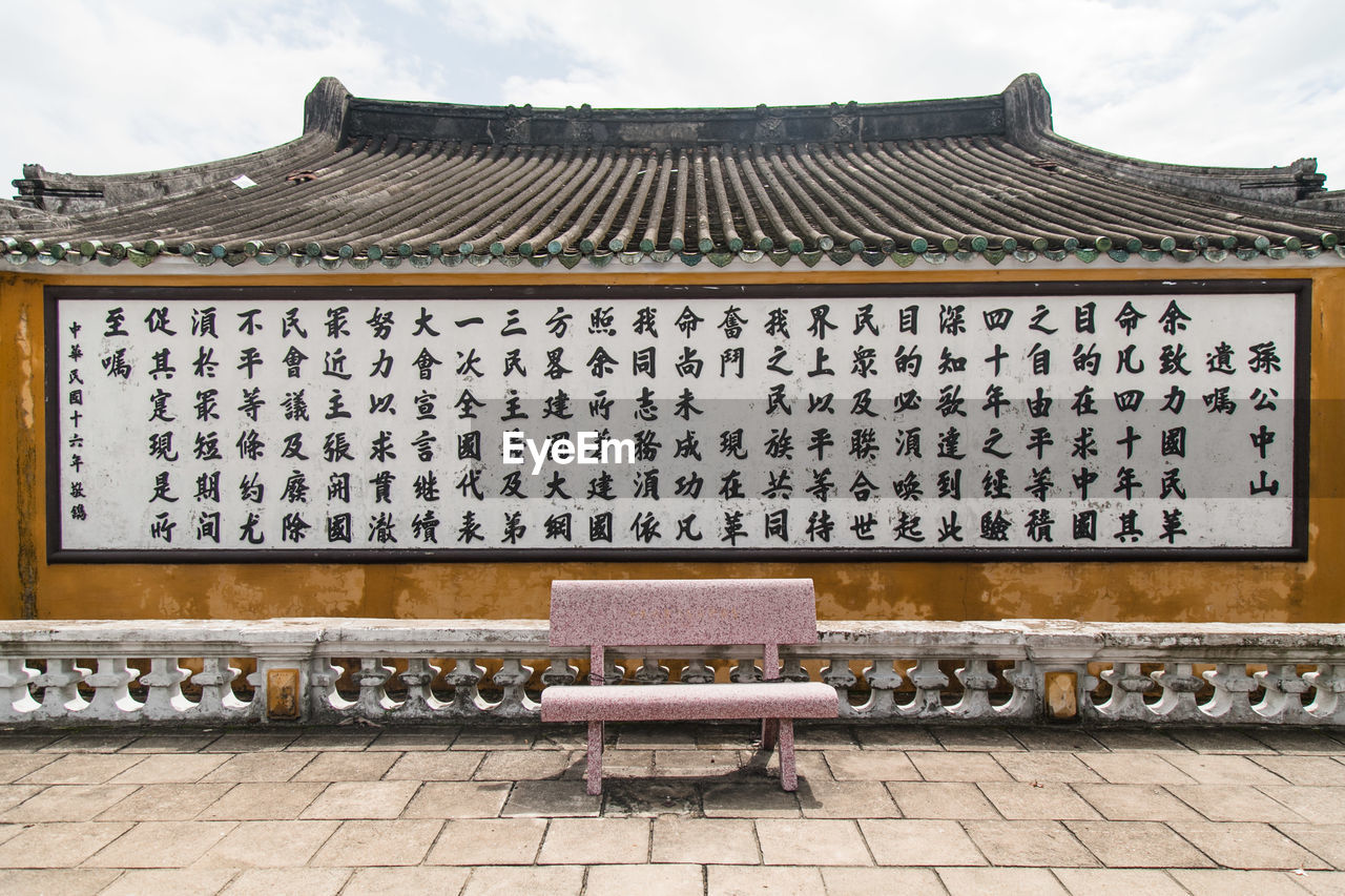 Bench against information sign on building 