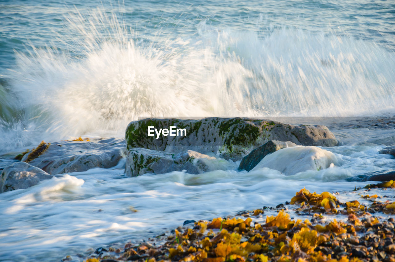 Scenic view of waves splashing on rocks at beach