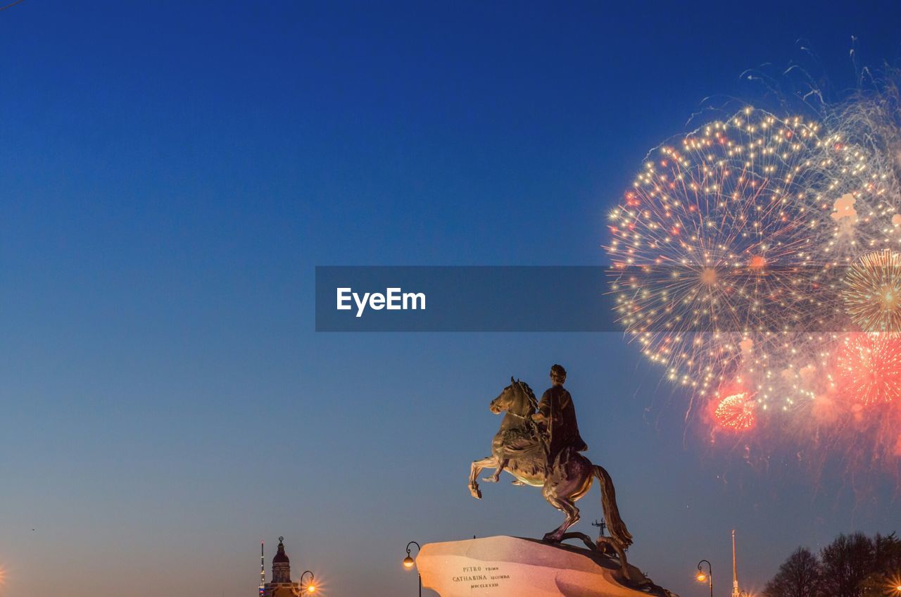 Bronze horseman against firework display at dusk