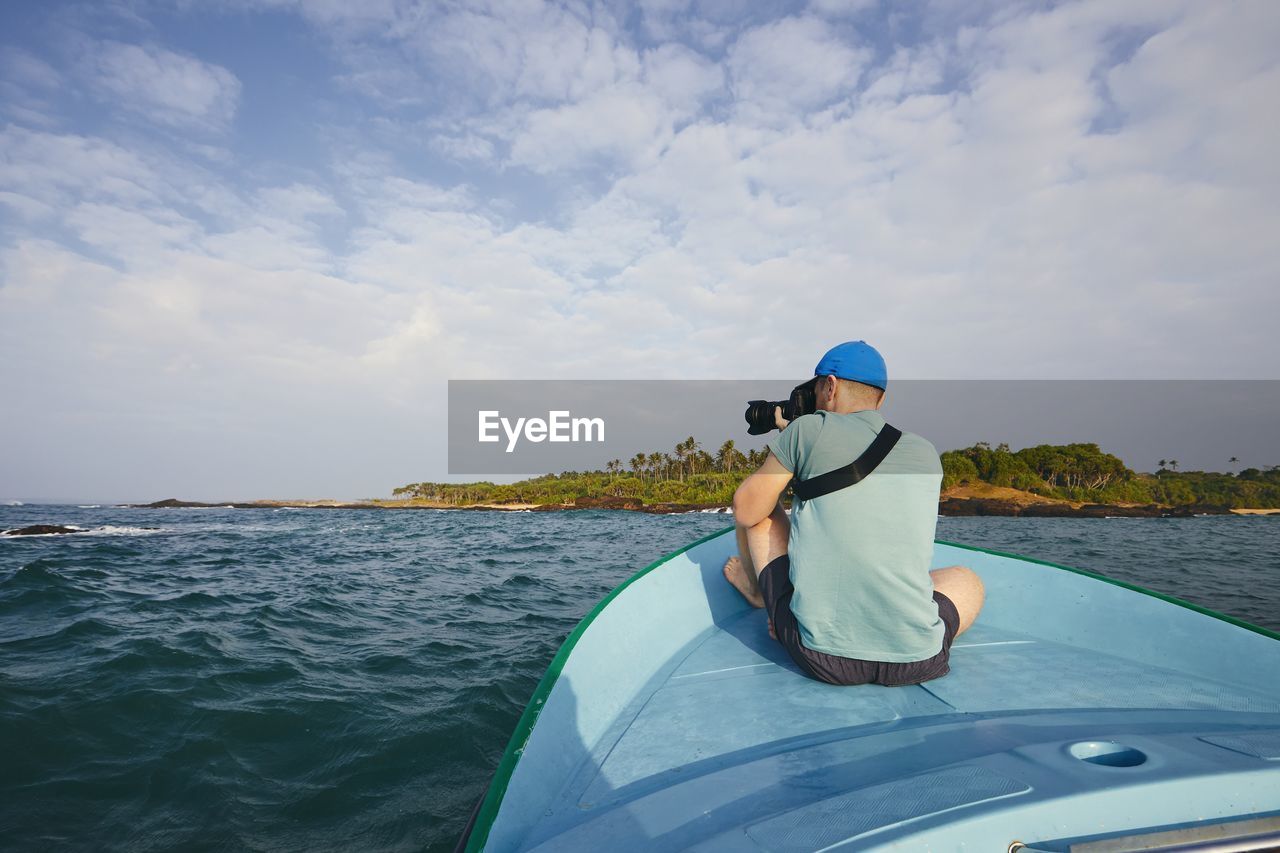 Rear view of man on boat in sea against sky