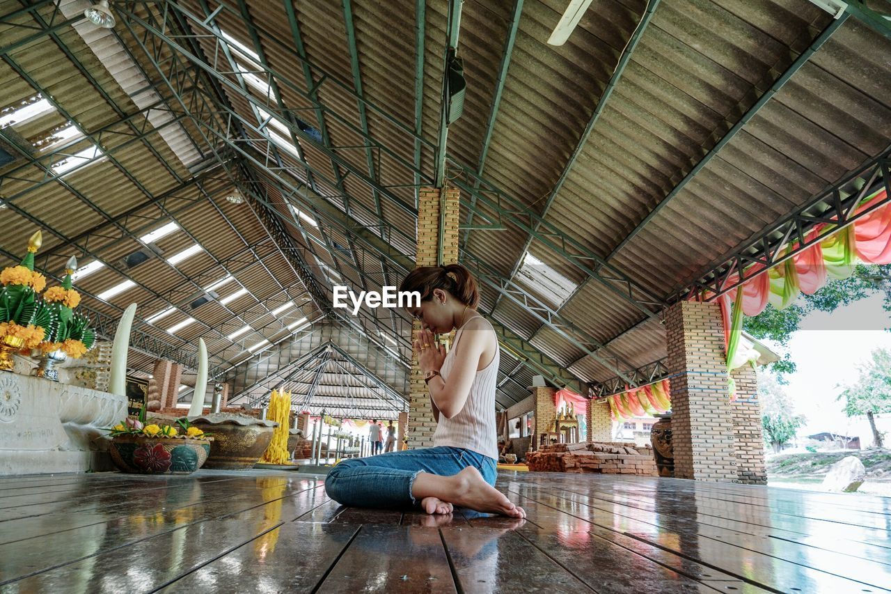 Full length of young woman sitting at temple