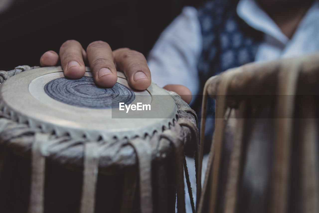 Midsection of man playing tabla against black background