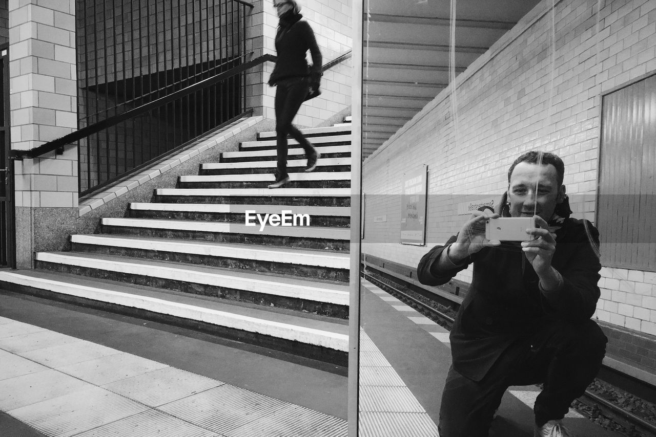 Reflection of man photographing by mirror at subway station